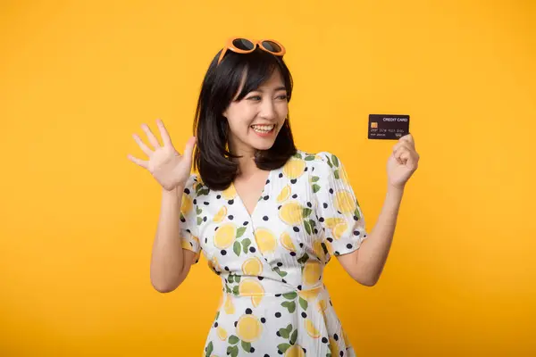 黄色の背景に隔離されたプラスチッククレジットカードを示す春のドレスで幸せな笑顔肖像アジアの若い女性 支払い お金と購入ショッピング支払いの概念 — ストック写真