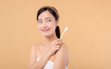 Sağlıklı gülümseyen genç bir kadının portresi. Elinde diş fırçası tutuyordu. Bej renkli stüdyo arka planında izole edilmişti. Diş temizliği, diş bakımı, diş bakımı..