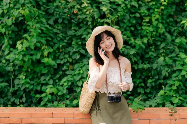 緑の公園の背景に帽子 バスケット 携帯電話やカメラを織って若いアジアの女性旅行者の肖像画 旅のライフスタイル 世界旅行探検家またはアジアの夏の観光コンセプト — ストック写真