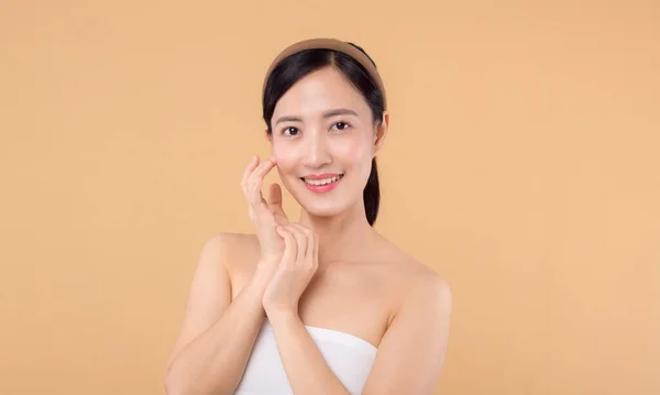 美丽的亚洲女孩模特在米色背景的特写下触摸鲜亮的水润面部肌肤 美容美发面对年轻女子 有着自然的妆容和健康的皮肤肖像 皮肤护理概念 — 图库照片