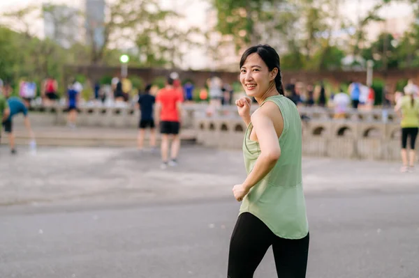 女慢跑者 为亚洲年轻女子提供绿色运动服健美操 在公园里跳舞 享受健康的户外生活 健身跑步的女孩在公共公园 健康是概念 — 图库照片
