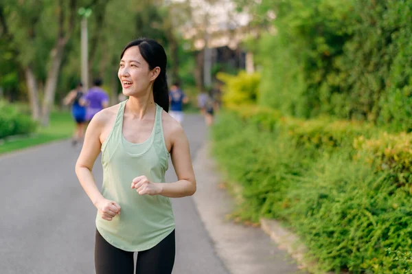 适合年轻的亚洲女子在公园里慢跑 面带微笑快乐地跑步 享受健康的户外生活 女慢跑者 健身跑步的女孩在公共公园 健康的生活方式和幸福的概念 — 图库照片