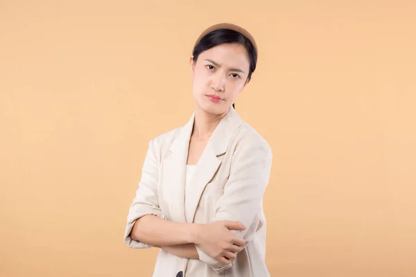 Studio portrait of successful happy confident young asian business woman. Beautiful young lady in white jacket smiling at camera standing isolated on solid beige colour copyspace background