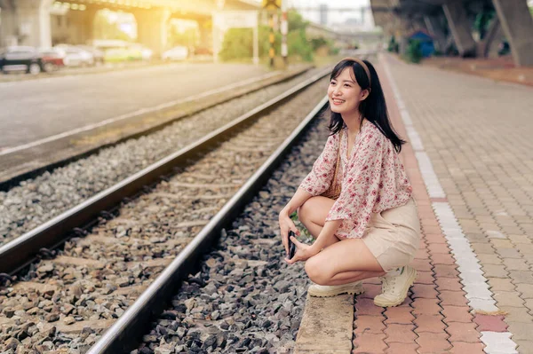 バンコクの鉄道駅の横にある携帯電話を使ってバスケットを編む若いアジアの女性旅行者 旅のライフスタイル 世界旅行探検家またはアジアの夏の観光コンセプト — ストック写真