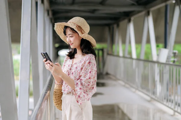 Азійська Молода Жінка Подорожує Кошиком Ткання Користуючись Мобільним Телефоном Стоїть — стокове фото