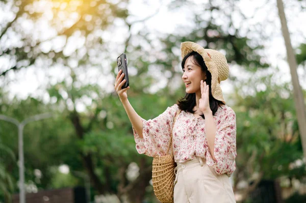 Portret Młodej Azjatyckiej Podróżniczki Tkającym Kapeluszem Koszykiem Przy Użyciu Telefonu — Zdjęcie stockowe