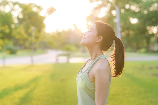 stock image Female jogger. Fit Asian young woman with green sportswear breathing fresh air in park before running and enjoying a healthy outdoor. Fitness runner girl in public park. Wellness being concept