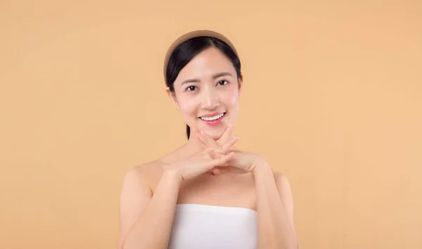 美丽的亚洲女孩模特在米色背景的特写下触摸鲜亮的水润面部肌肤 美容美发面对年轻女子 有着自然的妆容和健康的皮肤肖像 皮肤护理概念 — 图库照片