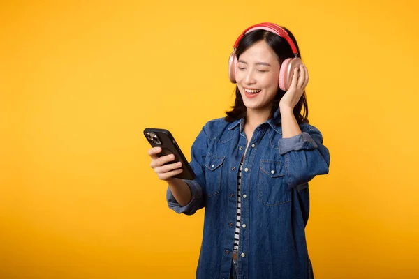 ポートレート若い陽気なアジアの女性は黄色に対するスマートフォン音楽アプリケーションによる音声を聞くことをお楽しみください ヘッドフォンで幸せな笑顔の女性の人 レジャー ライフスタイル テクノロジーの概念 — ストック写真