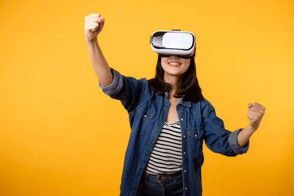 stock image Asian young woman happy success wearing virtual reality headset game entertainment isolated on yellow background. Winner of cyber future video game concept.