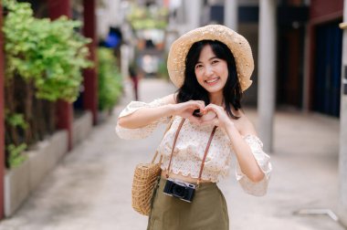 Kameralı mutlu Asyalı genç kadın hafta sonu şehir gezisine çıkıyor. Genç hippi bayan turist yaz Bangkok 'u geziyor. Asya yaz turizmi kavramı.