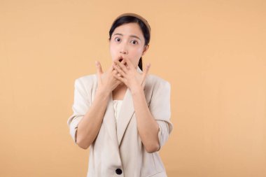 Başarılı, kendinden emin Asyalı genç iş kadınının stüdyo portresi. Beyaz ceketli güzel bir bayan kameraya gülümsüyor. Katı bej renkli arka planda tek başına duruyor.