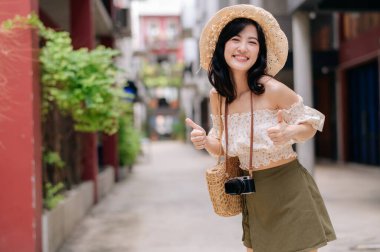 Kameralı mutlu Asyalı genç kadın hafta sonu şehir gezisine çıkıyor. Genç hippi bayan turist yaz Bangkok 'u geziyor. Asya yaz turizmi kavramı.