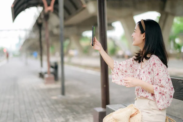 亚洲年轻女性旅行者 带着编织篮子 用手机 在火车站等火车 旅行生活方式 世界旅游探险家或亚洲夏季旅游概念 — 图库照片