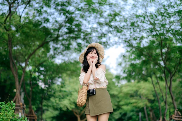 帽子とバスケットを織る若いアジアの女性旅行者の肖像画や緑の公園の自然背景にカメラ 旅のライフスタイル 世界旅行探検家またはアジアの夏の観光コンセプト — ストック写真
