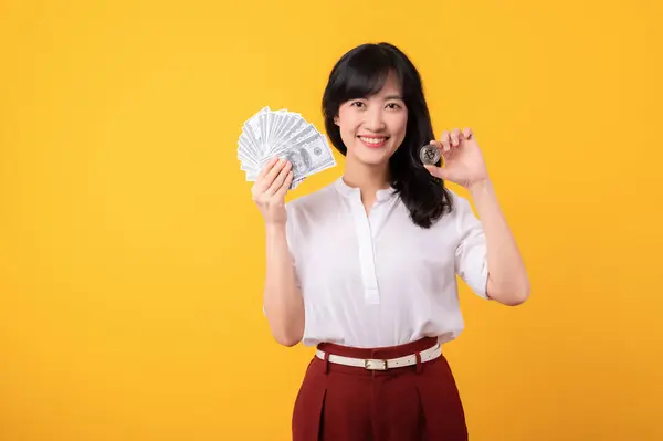 年轻美丽的亚洲女企业家的画像 身穿白衬衫 头戴红色的植物 头戴现金美元钞票 背景为黄色的数码货币隔离 脸上挂着幸福的笑容 财富概念 — 图库照片