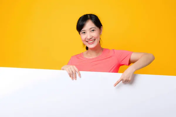 亚洲年轻的运动健美女子快乐地笑着 身穿粉色运动服 站在白色空白横幅或黄色背景的空空间广告板后面 福利生活方式概念 — 图库照片