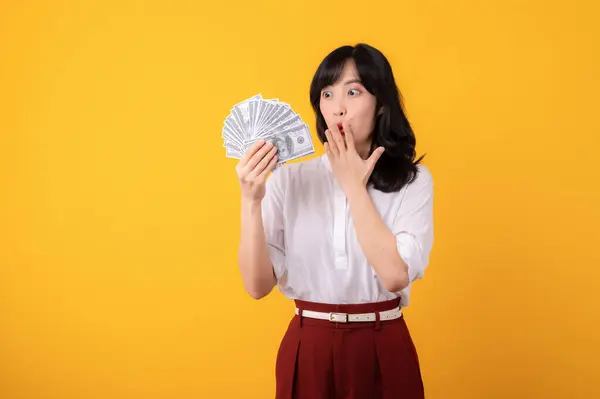 年轻美丽的亚洲女企业家面容迷人 身穿白衬衫 头戴红色植物 背景为黄色 背景为现金美元隔离 资金在线支付概念 — 图库照片