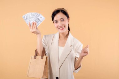Beyaz ceketli, para dolu beyaz ceketli ve bej arka planda duran başarılı, kendine güvenen genç Asyalı iş kadınının portresi. Çevre dostu alışveriş kavramı.