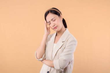 Başarılı, kendinden emin Asyalı genç iş kadınının stüdyo portresi. Beyaz ceketli güzel bir bayan kameraya gülümsüyor. Katı bej renkli arka planda tek başına duruyor.