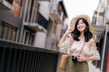 Kameralı mutlu Asyalı genç kadın hafta sonu şehir gezisine çıkıyor. Genç hippi bayan turist yaz Bangkok 'u geziyor. Asya yaz turizmi kavramı.