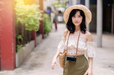 Kameralı mutlu Asyalı genç kadın hafta sonu şehir gezisine çıkıyor. Genç hippi bayan turist yaz Bangkok 'u geziyor. Asya yaz turizmi kavramı.