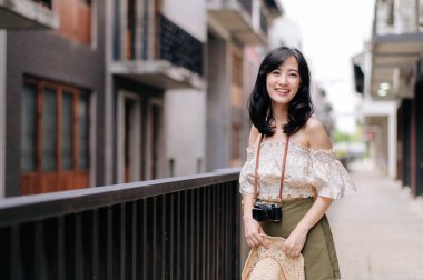 Kameralı mutlu Asyalı genç kadın hafta sonu şehir gezisine çıkıyor. Genç hippi bayan turist yaz Bangkok 'u geziyor. Asya yaz turizmi kavramı.