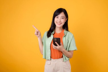 30 'larında Asyalı neşeli bir kadın. Turuncu gömlek giyiyor, akıllı telefon kullanırken bedava fotokopi için parmak gösteriyor. Promosyon amaçları ve dijital pazarlama kavramında çok yönlülük.