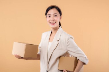 Başarılı, kendinden emin, beyaz ceketli genç Asyalı iş kadınının portresi bej renkli stüdyo arka planında izole edilmiş paket kutusu teslimat kuryesi ve nakliye hizmeti konsepti..