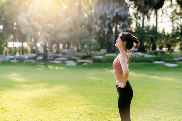 女慢跑者 为清新的跑步做准备 拥抱健康的户外生活方式 健康的亚洲30多岁的年轻女性穿着粉色运动服 在公园里舒缓呼吸 体现健康的理念 — 图库照片