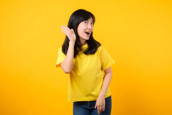 アジアの若い女性の注目を集める 黄色いTシャツとデニムジーンズを着て 耳を傾け 好奇心と興味を呼び起こします 注目を集めるプロモーションと割引 — ストック写真