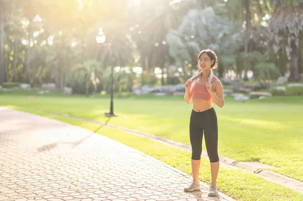 Female jogger. Active young 30s Asian woman in pink sportswear enjoys a morning workout in nature. active and live a healthy lifestyle concept.