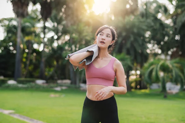 Happy 30s asian young woman wearing pink sportswear and jogging in nature. Captures the joy of a morning run and would be perfect for any project promoting fitness, health, or a healthy lifestyle.