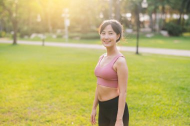 30 'lu yaşlarda koşan mutlu bir kadın koşucunun keyfini çıkar. Pembe spor giyimli Asyalı bir kadın halka açık bir parkta temiz havanın tadını çıkarıyor. Yaşarken ve doğayla bağlantı kurarken refahı kucaklayın..