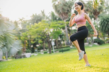 Sağlık ve sağlıklı Asyalı 30 'lu yaşlarda bir kadın güneş batarken halka açık parkta pembe spor giyim egzersizleri yapıyor. sağlıklı açık hava yaşam tarzı ve refah ve refah kavramı.