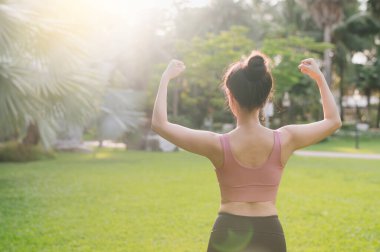 Güçlü bayan koşucu, formda 30 'lu yaşlarda Asyalı bir kadın. Pembe spor kıyafetler giyiyor. Parkta güçlü bir vücut var. Sağlıklı açık hava fitness koşucusu kız, günbatımında. Refah ve refah kavramı.