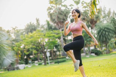 30 'lu yaşlarındaki Asyalı bir kadın güneş batımında halka açık bir parkta spor kıyafetleriyle egzersiz yapıyor. Sağlıklı bir açık hava yaşam tarzını benimse ve refahın ve refahın faydalarını keşfet..