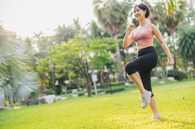 30 'lu yaşlarındaki Asyalı bir kadın güneş batımında halka açık bir parkta spor kıyafetleriyle egzersiz yapıyor. Sağlıklı açık hava yaşam tarzını benimseyin ve refahın ve refahın faydalarını keşfedin..