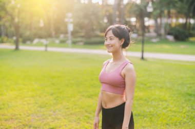 30 'lu yaşlarda koşan mutlu bir kadın koşucunun keyfini çıkar. Pembe spor giyimli Asyalı bir kadın halka açık bir parkta temiz havanın tadını çıkarıyor. Yaşarken ve doğayla bağlantı kurarken refahı kucaklayın..