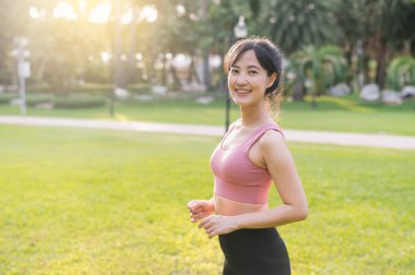 Mutlu, güzel bir Asyalı kadın olarak sağlıklı yaşam sürmeyi deneyin 30 'lu yaşlarda gülümseyen ve gün batımında parktaki kameraya bakan. Refah kavramını benimse.