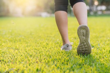 Koşucu kadın. Kamu parkında çimenler üzerinde spor koşucusu olarak yetişen genç bir bayan ayakkabısı. Fitness ayak ve bacak egzersizi sporcusu. Doğa maratonu. aktif sağlıklı yaşam tarzı çalışma konsepti.