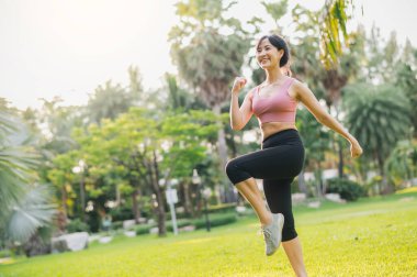 Güç, 30 'lu yaşlarda, pembe spor giyimli genç Asyalı bir kadının güneş batarken parkta güçlü bir vücudu olduğunu gösteriyor. sağlıklı açık hava yaşam tarzı ve sağlık ve refah konsepti fitness koşucusu kız sayesinde..