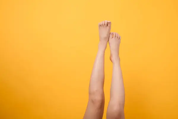 沉醉在雅致的天鹅绒般的触感中 30多岁的人的紧密腿在一个充满活力的黄色背景下 柔滑的脚的概念 — 图库照片
