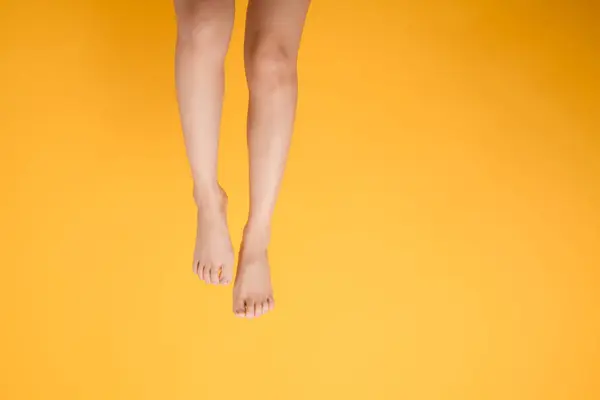 在生机勃勃的黄色背景下 用优雅的30多岁的人的紧密腿 发现光滑柔软的触摸的魅力 柔嫩柔滑的脚部概念 — 图库照片