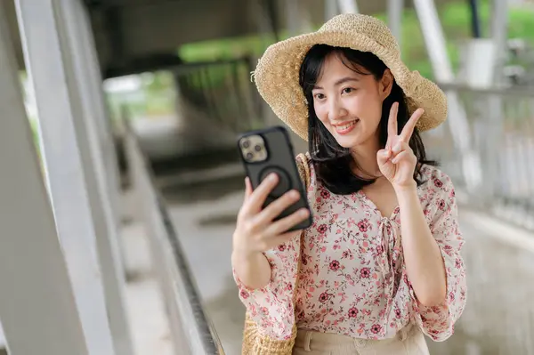 亚洲年轻女性旅行者 带着编织篮自拍 手持手机 站在天桥上 旅行生活方式 世界旅游探险家或亚洲夏季旅游概念 — 图库照片