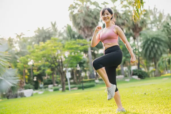 concept of wellness and well-being fit Asian woman 30s wearing pink sportswear exercising in public park at sunset. healthy outdoor lifestyle, wellness and well-being.