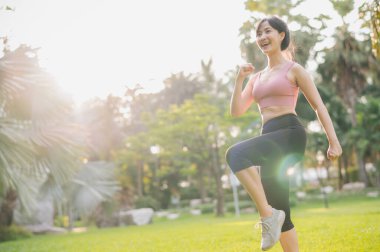 Kendini sağlıklı ve sağlıklı bir Asyalı kadın olarak 30 'lu yaşlarda pembe spor giyerek gün batımında halka açık parkta egzersiz yapma fikrine ver. Sağlıklı bir yaşam tarzının ilham verici gösterisi..