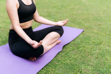 Serene Yoga Yolculuğu. Lotus pozuyla dengelenmiş bir kadın, ormanın sakin yeşilliğinin ortasında yoga yapıyor, doğanın dinginliğini kucaklıyor..