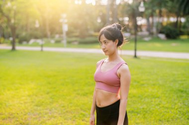 30 'lu yaşlarda sağlıklı ve mutlu bir Asyalı kadınla birlikte doğada yaşamak. Pembe spor giyer ve halka açık bir parkta koşarken temiz hava solur..