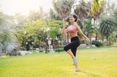30 'lu yaşlardaki Asyalı kadın güneş batarken halka açık bir parkta pembe spor giysi egzersizi yapıyor. Sağlıklı bir açık hava yaşam tarzını benimseyin ve sağlığınıza ve sağlığınıza öncelik verin..